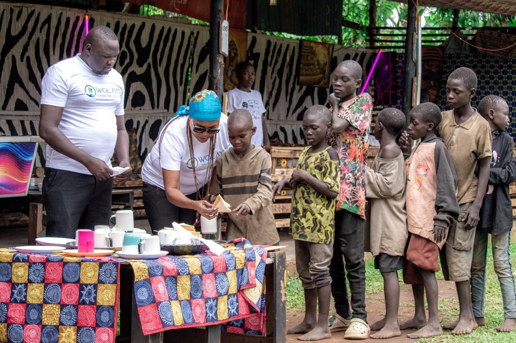 Wolayo volunteers in branded shirts serving bread to children at a community gathering.
