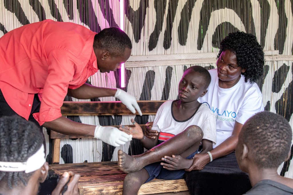 Medical outreach: a caregiver tends to a child's leg while a Wolayo team member offers support.